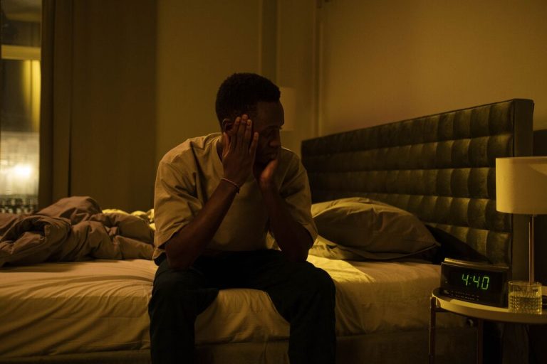 homem sentado na cama sem conseguir dormir